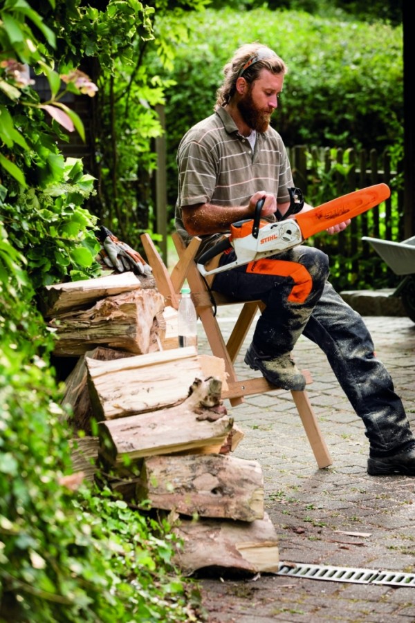 Un homme assis sur un chevalet avec sa tronçonneuse